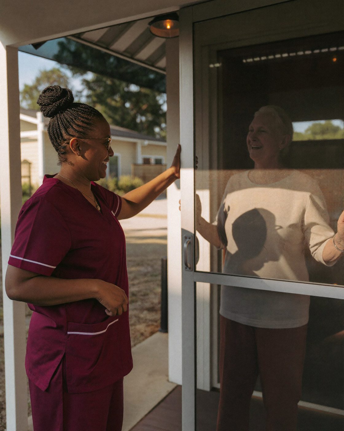 A caregiver greeting an older woman at her front door in Little Rock