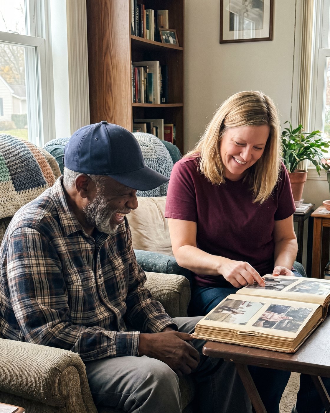 An older veteran and his caregiver laughing over a family photo album at home